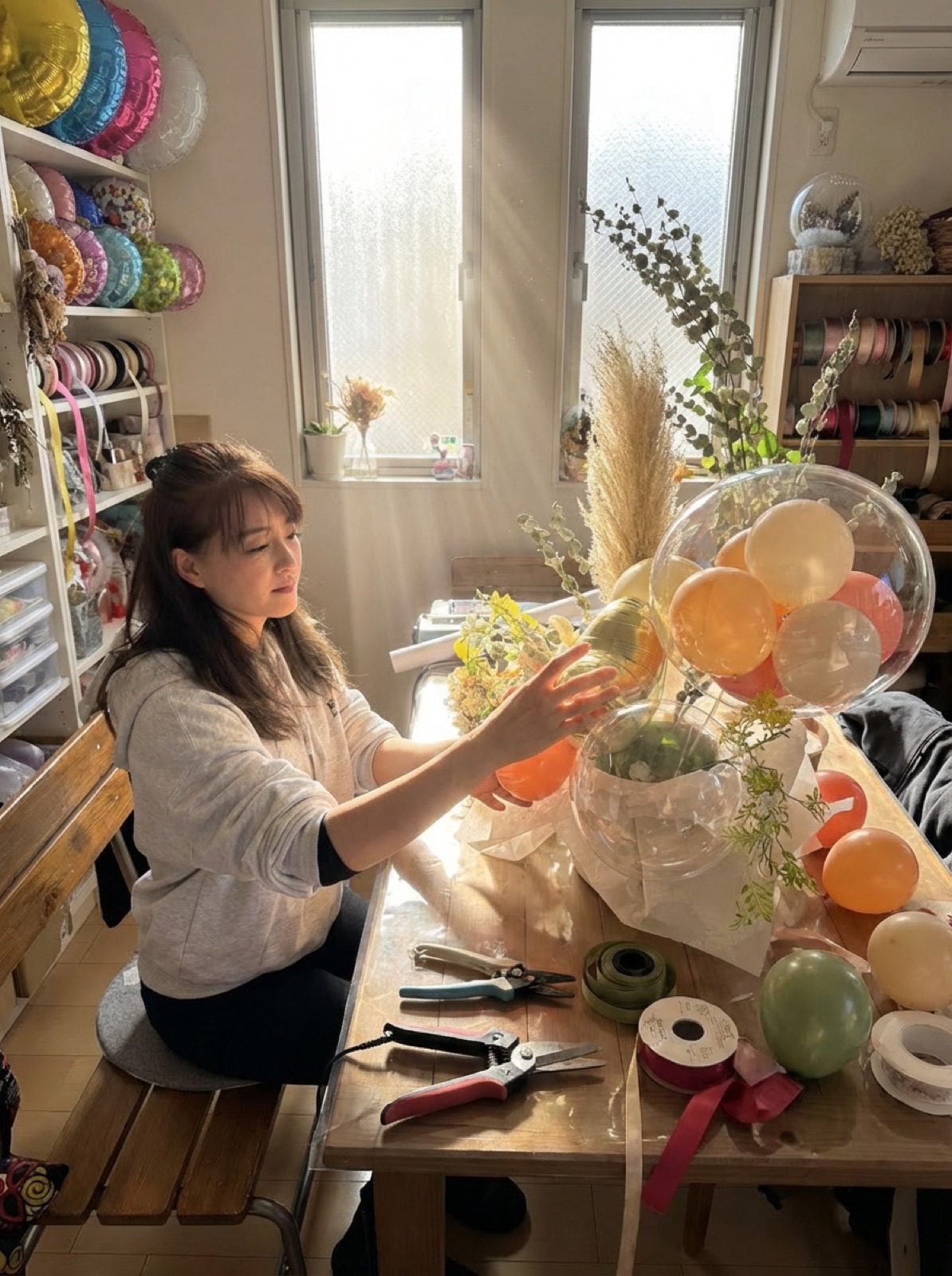 窓ぎわの作業台でバルーンアレンジを仕上げるつくり手